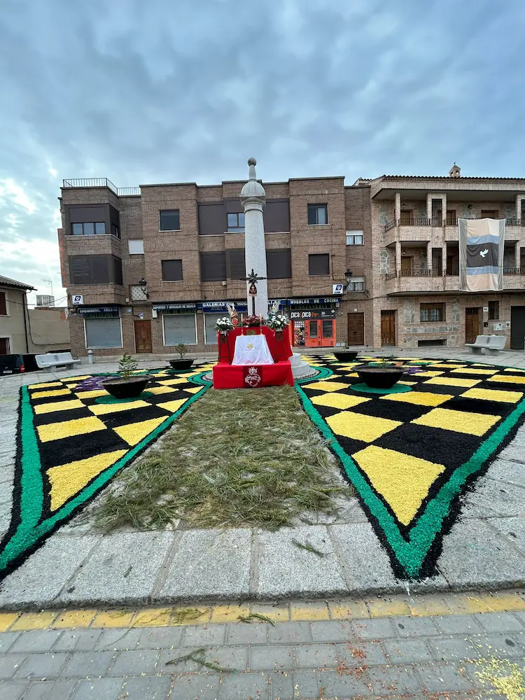 Alfombra central en la Plaza del Ayuntamiento de Los Navalmorales para el Corpus Christi 2025, con motivos geométricos amarillos y negros