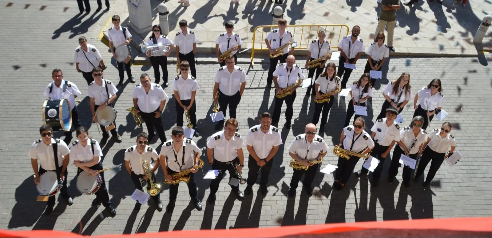 Desfile de la banda en la fiesta local con cielo despejado al fondo, 2024
