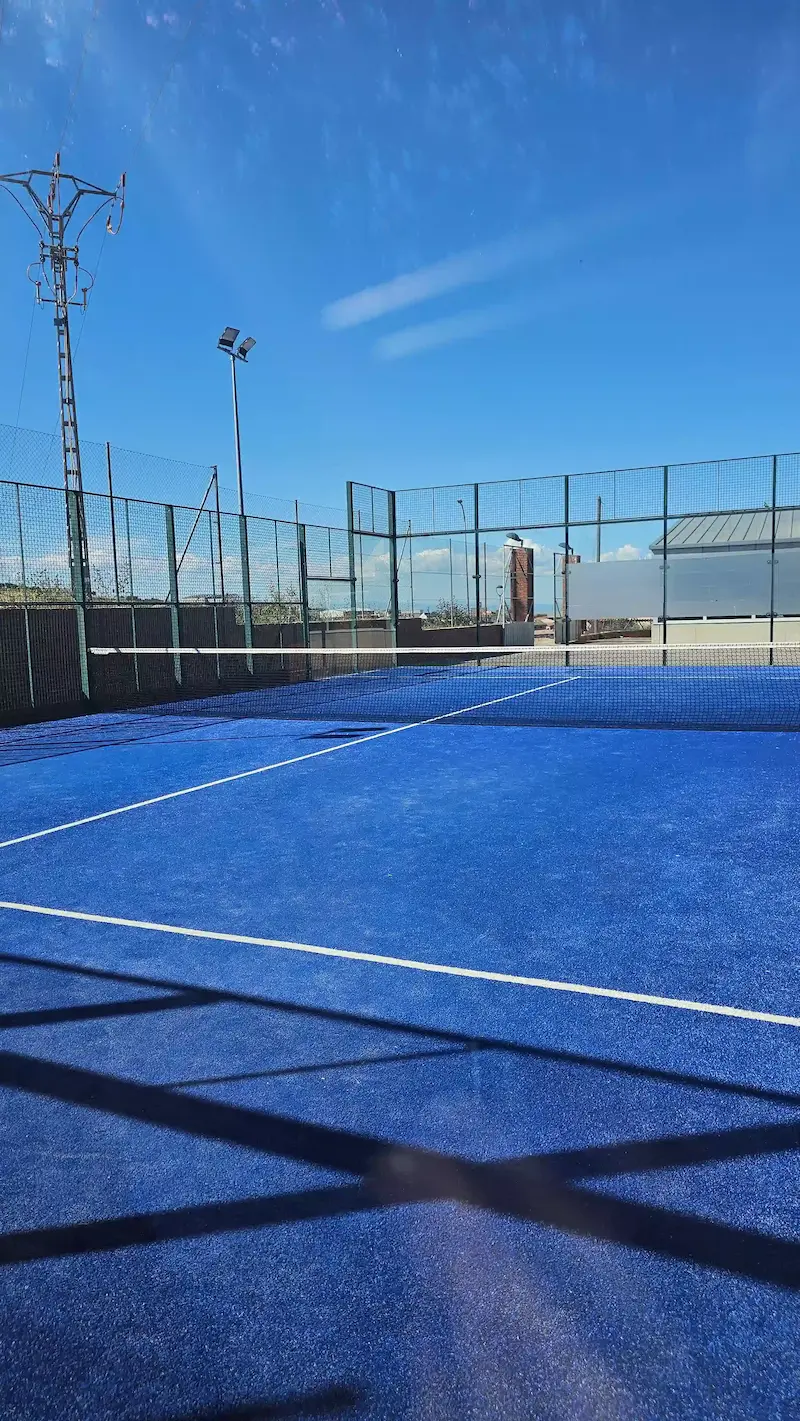 Vista de la pista de pádel municipal de Los Navalmorales con césped azul y red central, lista para jugar