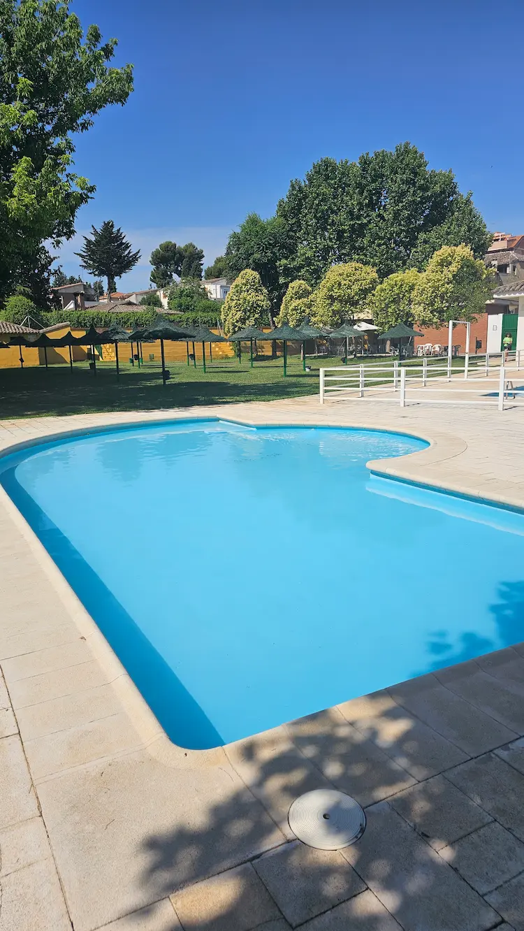 Piscina infantil de Los Navalmorales junto a amplias zonas de césped y sombra, perfecta para familias con niños.