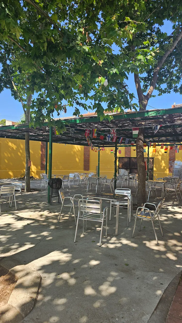 Terraza del bar de la piscina municipal de Los Navalmorales con mesas y sombra.