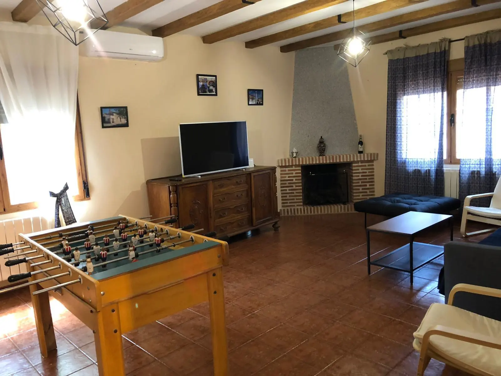Salón principal con futbolín, chimenea y televisión en La Chocolatera