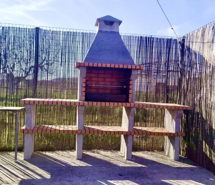 Zona de barbacoa exterior con parrilla de obra en La Fragua del Sauce