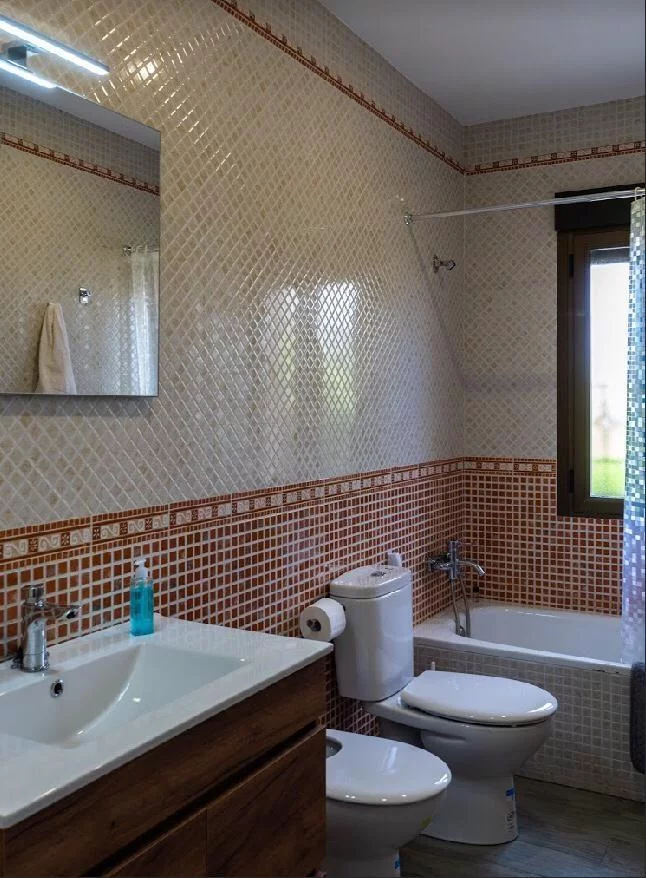 Baño adicional con bañera, lavabo doble y azulejos decorativos en La Fragua del Sauce