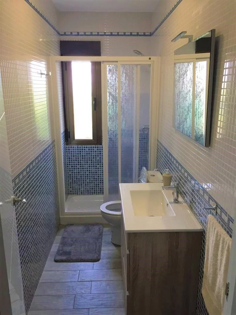 Baño moderno con ducha amplia, lavabo y ventana exterior en La Fragua del Sauce