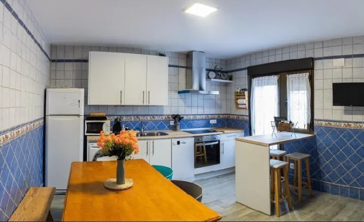 Cocina equipada con mesa de madera, electrodomésticos y ventana exterior en La Fragua del Sauce