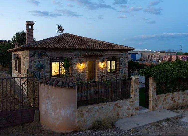 Fachada iluminada de La Fragua del Sauce al anochecer, con detalles en piedra y tejas